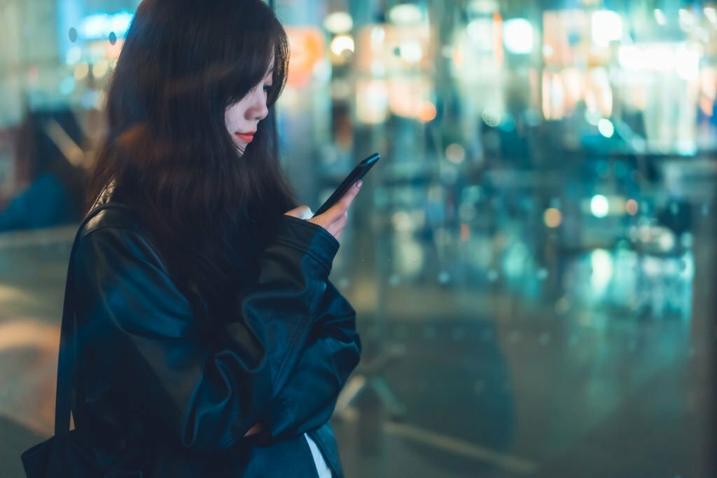 Asian woman in city using smart phone.